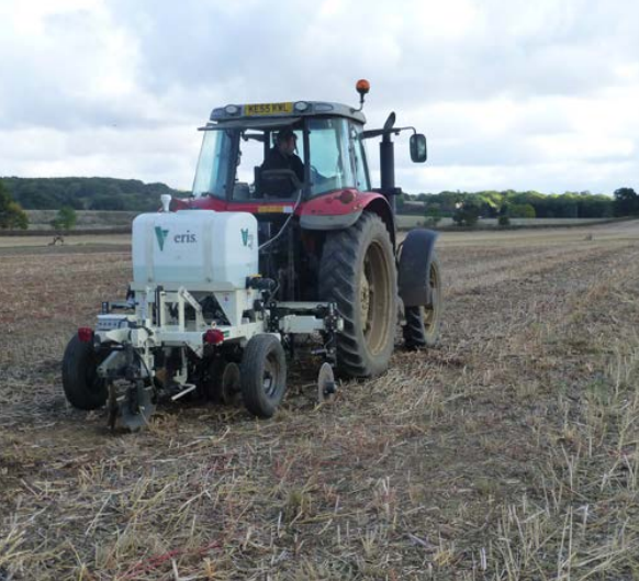Farmer driving red tractor through field of crop